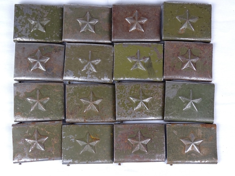 May include: A collection of 18 vintage metal belt buckles with a star design. The buckles are green and have a worn, rusty appearance.