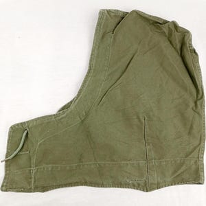 May include: A green canvas hooded jacket with a drawstring closure. The hood is lined with a brown fabric.