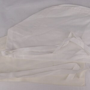 May include: Two white surgical scrub caps with ties. The caps are made of a lightweight fabric and are designed to cover the hair during medical procedures. The ties allow for an adjustable and secure fit.