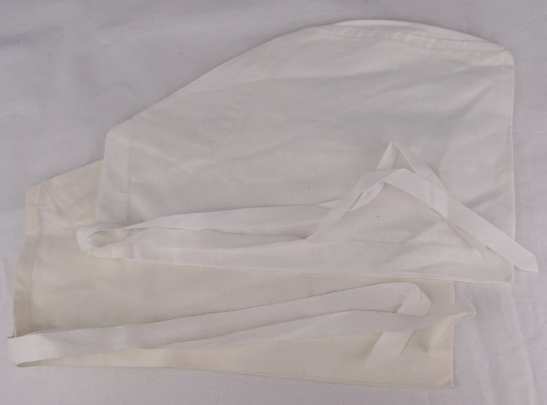 May include: Two white surgical scrub caps with ties. The caps are made of a lightweight fabric and are designed to cover the hair during medical procedures. The ties allow for an adjustable and secure fit.