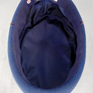 Pu&ograve; includere: Un cappello blu navy con una corona arrotondata e una fodera in raso blu scuro. Il cappello ha un esterno strutturato e un bordo in gros-grain. L'etichetta all'interno recita "Lise Davril Paris" e include la taglia "55".