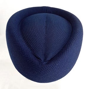 Pu&ograve; includere: Un cappello blu navy con una corona arrotondata e un tessuto strutturato. Il cappello ha un bordo circolare e una parte superiore leggermente rialzata. Il cappello &egrave; realizzato in un materiale tessuto ed &egrave; di colore uniforme.