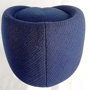 Pu&ograve; includere: Un cappello blu navy con una corona arrotondata e una base cilindrica. Il cappello ha un aspetto in tessuto strutturato e tessuto. Il cappello &egrave; di colore pieno e sembra essere fatto di un materiale robusto.