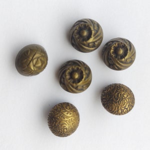 May include: Six antique gold-toned buttons with intricate floral designs. The buttons are round and have a raised, textured surface.