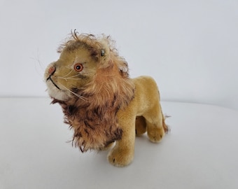 Puede incluir: Un juguete de peluche vintage en forma de león con una melena marrón y un cuerpo marrón claro. El león tiene ojos naranjas y una nariz cosida.