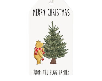 May include: A white gift tag with a cartoon illustration of Winnie the Pooh decorating a Christmas tree. The tag reads "Merry Christmas" and "From: The Pegg Family".