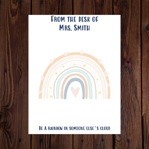 May include: A white card with a rainbow design and the text "From the desk of Mrs. Smith" at the top and "Be a rainbow in someone else's cloud" at the bottom.