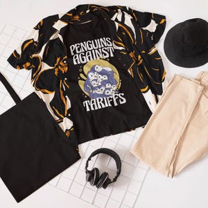 Könnte beinhalten: Schwarzes T-Shirt mit einem Aufdruck von Pinguinen und dem Text "Penguins Against Tariffs". Das T-Shirt wird mit einem schwarz-weißen Hemd mit Blumenmuster, einer beigefarbenen Hose, einem schwarzen Bucket-Hut und einer schwarzen Tragetasche kombiniert.