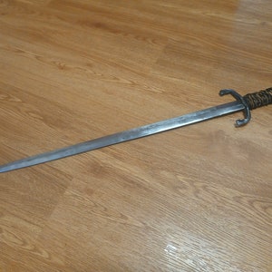 May include: A silver sword with a brown leather wrapped handle. The sword has a double-edged blade and a pointed tip.