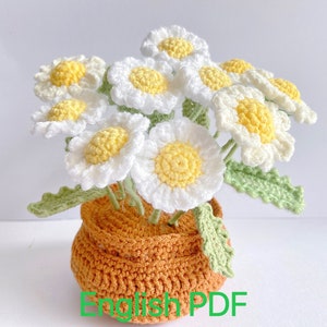 May include: A crocheted bouquet of white daisies with yellow centers in a brown crocheted pot. The daisies have green crocheted leaves.