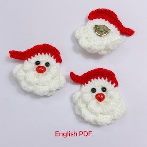 May include: Three crocheted Santa Claus ornaments with red hats and white beards. The ornaments have black eyes and red noses. The ornaments are on a white background. English PDF.