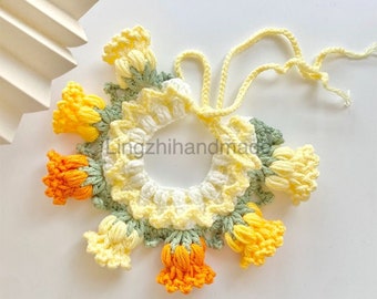 May include: A crocheted flower collar with yellow, white, and green yarn. The collar has a tie closure and is decorated with crocheted flower accents.