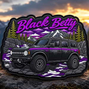 May include: A black SUV patch featuring the text Black Betty in purple script. The design includes a mountain landscape with green pine trees, rocky terrain, and purple accents. The vehicle is a four-door model with off-road tyres and a purple stripe.