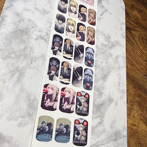 May include: A strip of nail art stickers featuring various anime character designs. The stickers showcase detailed illustrations of characters with diverse hairstyles and expressions. The text "DEATH NOTE" is visible on some stickers.