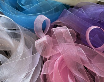 May include: Assortment of sheer ribbon in various pastel colors, including pink, blue, purple, and white. The ribbon has a subtle shimmer and is perfect for crafting and decorating.