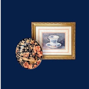 Puede incluir: Un plato decorativo ovalado con un diseño de pájaro y flores en tonos dorados, melocotón y negro. También se ve una pintura en acuarela enmarcada de una taza y un platillo con detalles florales azules.