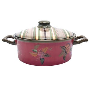 Può includere: Una pirofila in ceramica rossa con coperchio. Il coperchio ha un motivo a righe nei toni del verde, beige e marrone. Il piatto è decorato con disegni floreali e di uva dipinti. Ha due manici marroni.