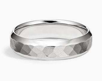 May include: A silver ring with a textured band. The band features a geometric pattern, and the ring has a polished, smooth interior. The ring is shown against a white background.