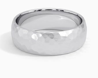 May include: A silver-colored ring with a hammered texture. The ring has a wide band and a polished interior. The surface of the ring has a textured, dimpled appearance, reflecting light. The ring is a piece of jewelry.