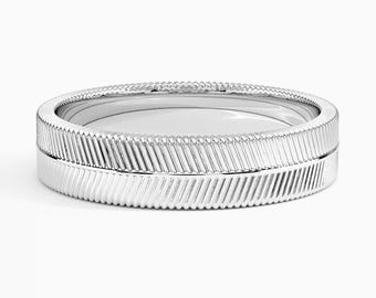 May include: A pair of silver rings with a textured, ridged design. The rings have a detailed pattern of diagonal lines around the edges, creating a unique and elegant look. The rings are set against a white background.