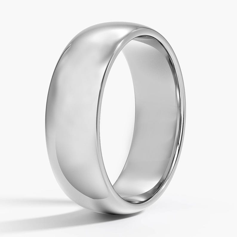 May include: A polished, silver-colored ring with a rounded, domed top and a smooth, reflective surface. The ring has a classic, simple design, and is set against a white background.