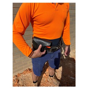 May include: A person wearing a bright orange long-sleeved shirt and blue shorts with a black tool belt and a black tool holder attached to the belt.