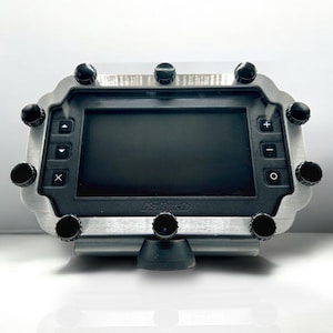 May include: A digital display device with a black screen and a brushed metal frame. The device has several black knobs around the perimeter and buttons on the front. The brand name "Haltech" is printed on the bottom of the screen.