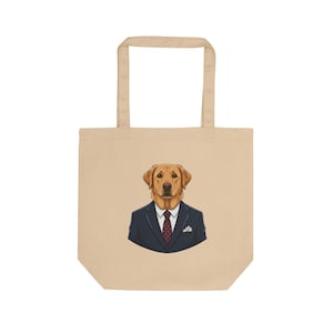 May include: Beige tote bag featuring a cartoon illustration of a Labrador Retriever wearing a navy blue suit, white shirt, and a red patterned tie. The dog's head is centered on the bag.