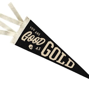 Può includere: Pennant in feltro nero con lacci in feltro bianco. Il pennant ha il testo "You are good as gold" in lettere bianche.
