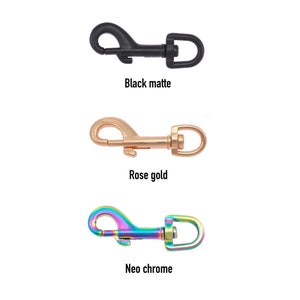 Könnte beinhalten: Drei Metallschließen in verschiedenen Ausführungen: Schwarz matt, Roségold und Neo-Chrom. Die Schließen sind alle gleich groß und haben die gleiche Form, mit einem federbelasteten Verschluss.