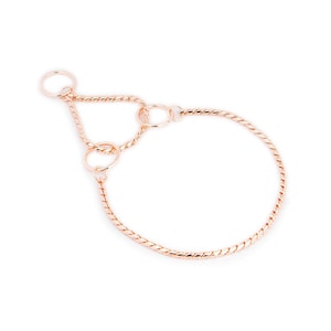 May include: A rose gold chain dog collar with a twisted design and multiple rings.
