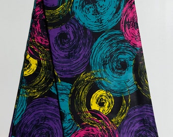 May include: Folded black fabric with a vibrant pattern of large, swirling circles in teal, purple, pink, and yellow. The design is set against a black background. The number "74011" is printed on the fabric.