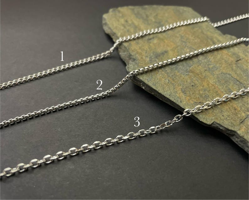 May include: Three silver-toned metal chains labeled with numbers one, two, and three. Chain one is a thin curb chain, chain two is a box chain, and chain three is a cable chain. Each chain features a distinct link style and metallic finish.
