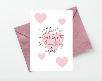 Puede incluir: Una tarjeta de felicitación blanca con un corazón rosa grande en el centro con el texto negro "All that I am or ever hope to be, I owe to my mother" y cuatro corazones rosas más pequeños rodeando el texto, sobre un sobre malva texturizado.