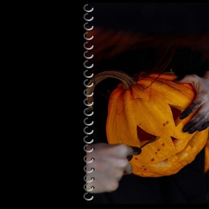 May include: A person carving a jack-o'-lantern with a knife. The pumpkin is orange and has a scary face carved into it.