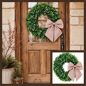 May include: A circular green boxwood wreath featuring a large, structured bow made of red and white gingham fabric. The wreath is displayed on a wooden door and also shown separately against a plain white background.