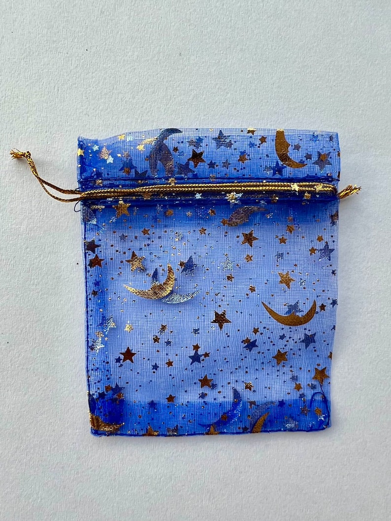 May include: A blue mesh gift bag with a gold drawstring and a pattern of gold stars and crescent moons.