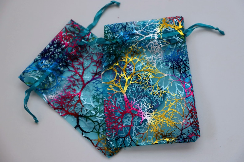 May include: Two turquoise organza gift bags with a colorful tree branch design. The bags have a drawstring closure.