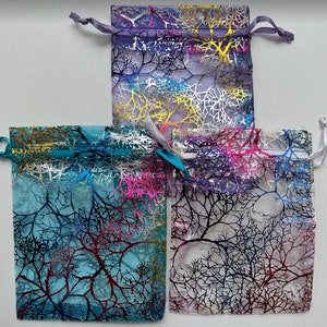 May include: Three sheer fabric gift bags with a tree branch design. The bags are in shades of purple, blue, and white.