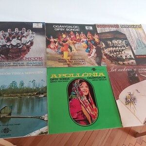 May include: A collection of seven vintage vinyl records with colorful covers featuring Hungarian folk music and dances. The records include titles like "Magy. Incok", "A Kanyarigos Tisza Menten", "Apollonia", "Ciganydalok", "Hungarian Folksongs", "Ciganydalok Gipsy Songs", and "Irt nekem a szeretőm".