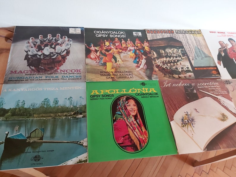 May include: A collection of seven vintage vinyl records with colorful covers featuring Hungarian folk music and dances. The records include titles like "Magy. Incok", "A Kanyarigos Tisza Menten", "Apollonia", "Ciganydalok", "Hungarian Folksongs", "Ciganydalok Gipsy Songs", and "Irt nekem a szeretőm".