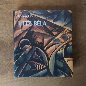 May include: Book cover with an abstract painting in shades of blue, green, brown, and yellow. The title "Uitz Béla" is printed in white on the cover, along with the author's name "Bajkay Éva".