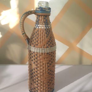Demijohn bottle, vintage glass bottle wrapped in multi-colored plastic wicker, whiskey bottle, wine bottle, demijohn bottle with handle.