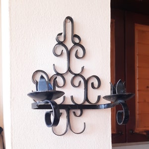 Vintage wrought iron wall sconce with ornaments. Hanging black candlestick, double wall sconce, primitive early candle lighting, gothic.