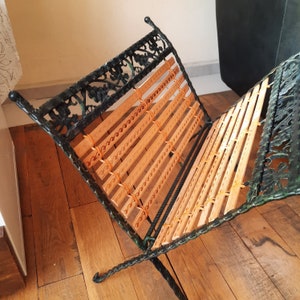 May include: A black metal magazine rack with a woven wood insert. The rack is folded and has a decorative design.
