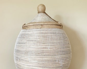 May include: A large, white and natural woven basket with a lid. The basket is oval shaped and has a natural wood knob on the lid.