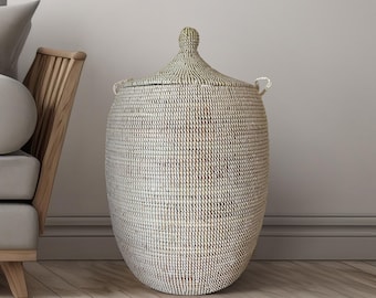 May include: A large, white and black woven storage basket with a lid and handles. The basket is made of natural materials and has a traditional design.