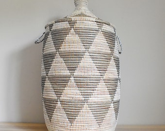 May include: A large, woven storage basket with a lid. The basket is made of natural materials and has a geometric pattern in shades of brown and white.