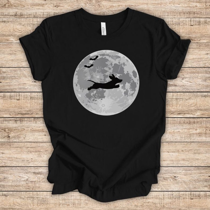 May include: Black t-shirt with a silhouette of a dachshund jumping in front of a full moon with bats flying overhead.