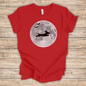 May include: Red t-shirt with a black silhouette of a dachshund jumping in front of a full moon with bats flying above.